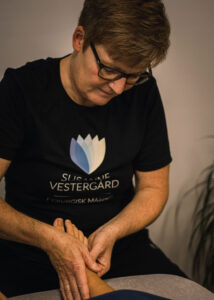 Behandler Susanne Vestergaard giver fodmassage mod uro, hvor hænderne blidt masserer fødderne for at skabe afslapning.