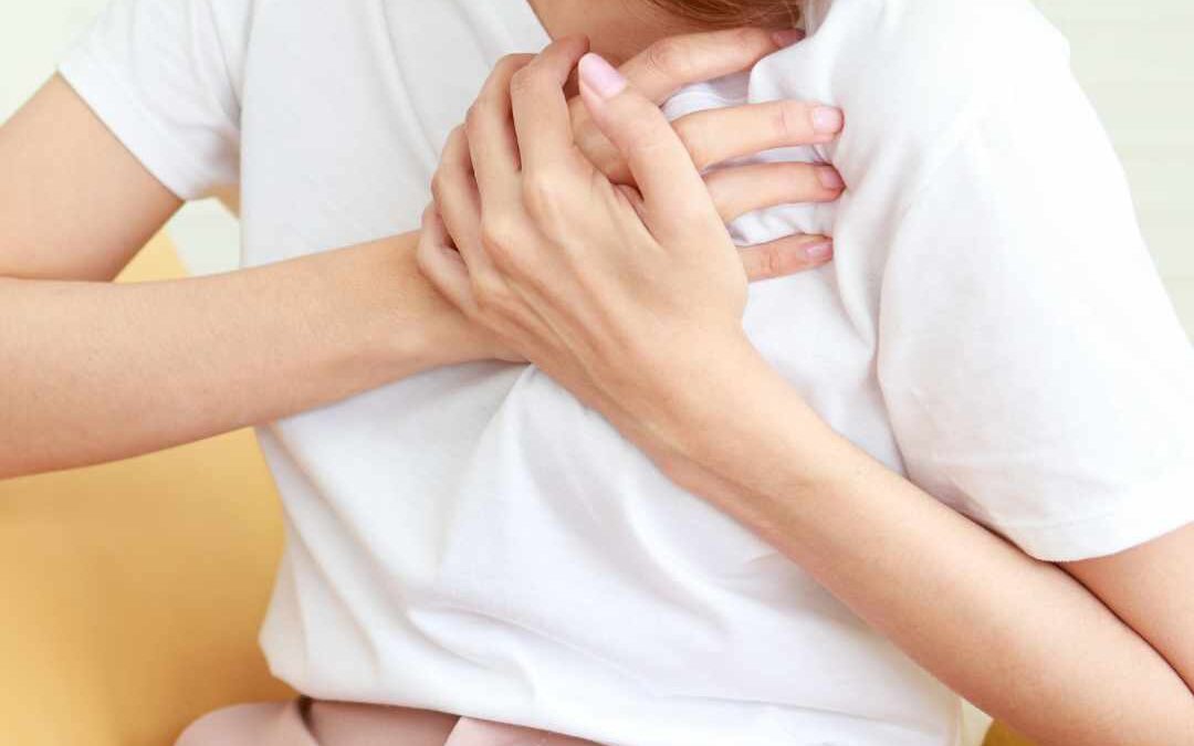 Kvinde holder sig til brystet, muligvis oplever angst eller stressrelaterede symptomer.