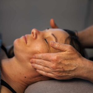 En behandler giver målrettet massage omkring kæbemuskulaturen for at afhjælpe kæbespændinger.