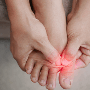 Person trykker på forfoden med begge hænder – tydeliggør smerter i forfod og tæer markeret med rødligt område.