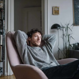 Mand sidder i stol med et fjernt blik, som et udtryk for behovet for behandling af tankemylder og mental ro.