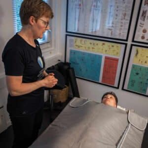 Behandling med infrarød saunatæppe hjælper kvinde med at reducere ubehag i kroppen og skabe afslapning.