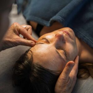 Kvinde får Access Bars behandling med blid berøring af hovedet – metode til at få hjernen til at slappe af.