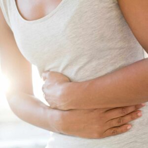 Kvinde holder sig til maven på grund af spændinger i maven, som kan skyldes stress, fordøjelsesproblemer eller muskelspændinger.