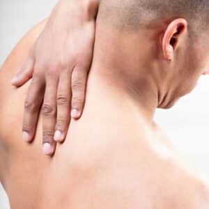 Mand med hånden på nakken som viser spændinger og ubehag hvad hjælper på hovedpine.