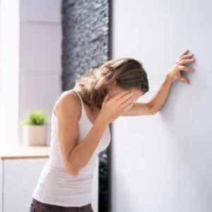 Kvinde støtter sig til væggen og oplever pludselig svimmelhed i hverdagen.