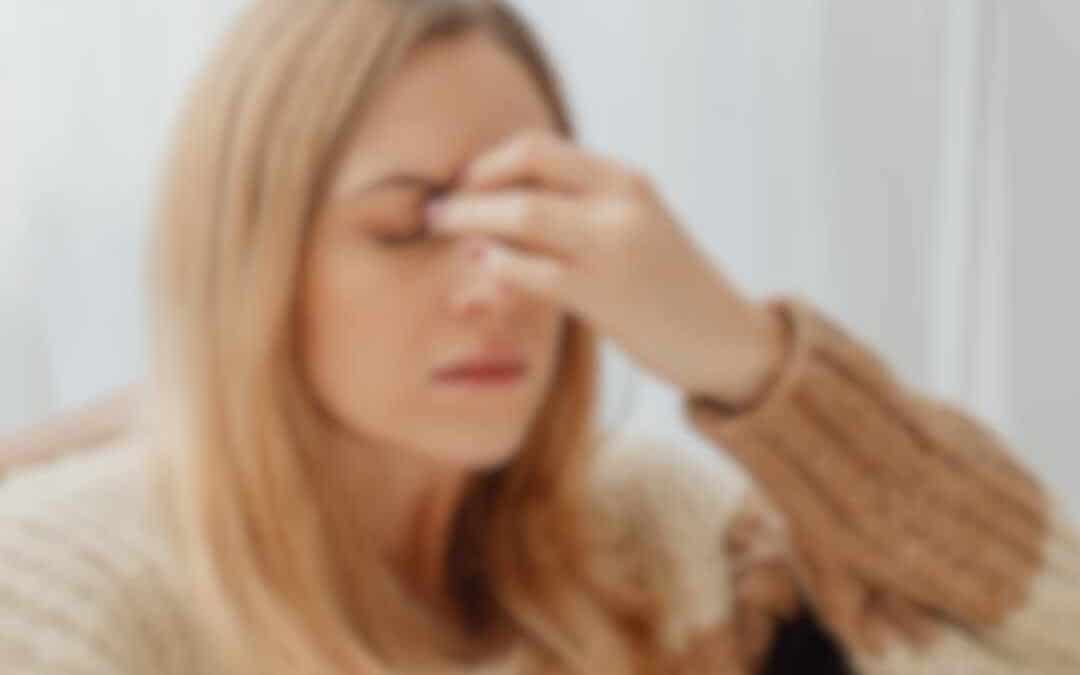 Kvinde der holder sig for panden med tydelige migrænesymptomer og behov for lindring af hovedpine.