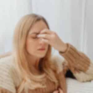 Kvinde der holder sig for panden med tydelige migrænesymptomer og behov for lindring af hovedpine.