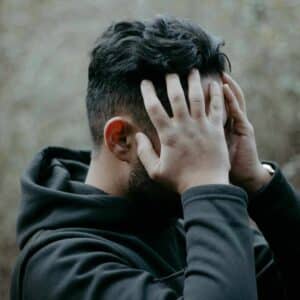 Mand med migræne holder begge hænder mod hovedet, som tegn på smerter og spørgsmålet om hvad hjælper på migræne.