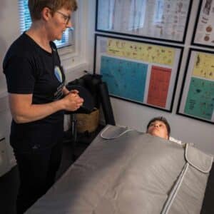 Klient modtager infrarød varmebehandling som lindring af stive led og muskelspændinger.