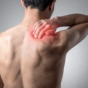 Mand med muskelsmerter i skulder og øvre ryg, markeret ved rødme og spænding.