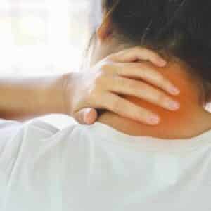 Kvinde med spændinger i nakken som årsag til nakkesmerter og hovedpine.