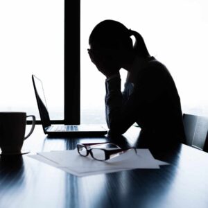Silhuet af kvinde med hovedet i hænderne som illustrerer stress symptomer hos kvinder.