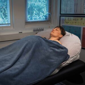 Gravid kvinde ligger afslappet på briks under behandling i klinik med fokus på velvære under graviditeten.