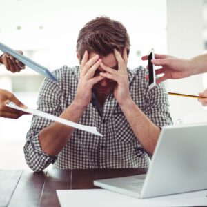 Stress på arbejdspladsen med presset medarbejder omgivet af arbejdsopgaver.