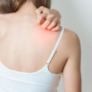 Kvinde med smerter og irritation i skulderen, som kan give behov for skuldermassage.